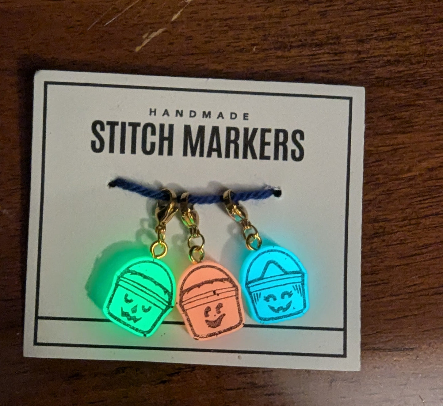 Set of colorful stitch markers on a card labeled 'Stitch Markers' on a wooden surface.